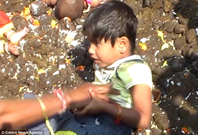 Parents roll children and babies in COW MANURE