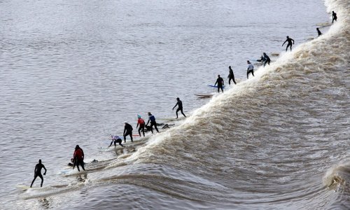 Surfers brave the cold for a group ride on a 20 mile wave - PHOTO