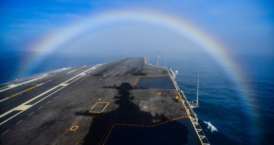 Photographer captures moment US Navy aircraft carrier steams through a rainbow